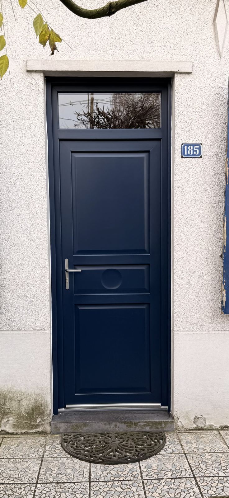 Porte d'entrée bleu nuit à panneaux sur façade claire