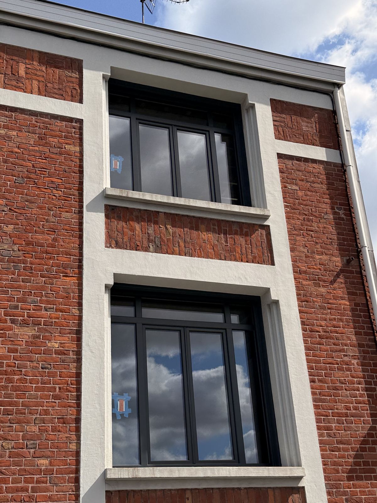 Façade en briques équipée de fenêtres aluminium anthracite sur deux niveaux
